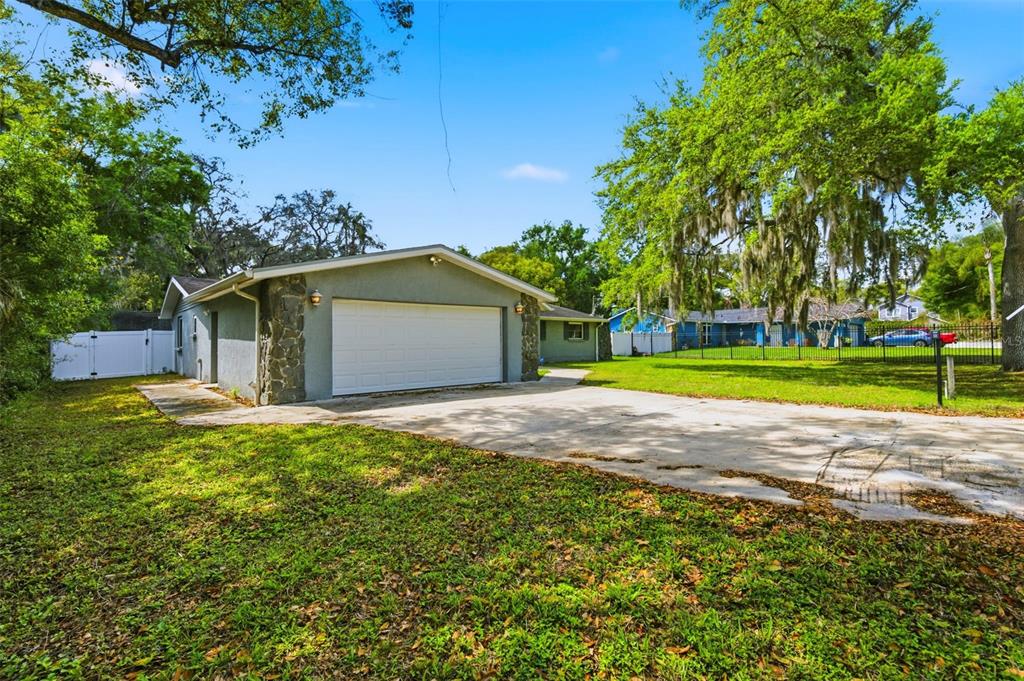 A detached garage with a white door and stone accents sits on a concrete driveway — 212 W 131ST AVENUE, TAMPA, FL