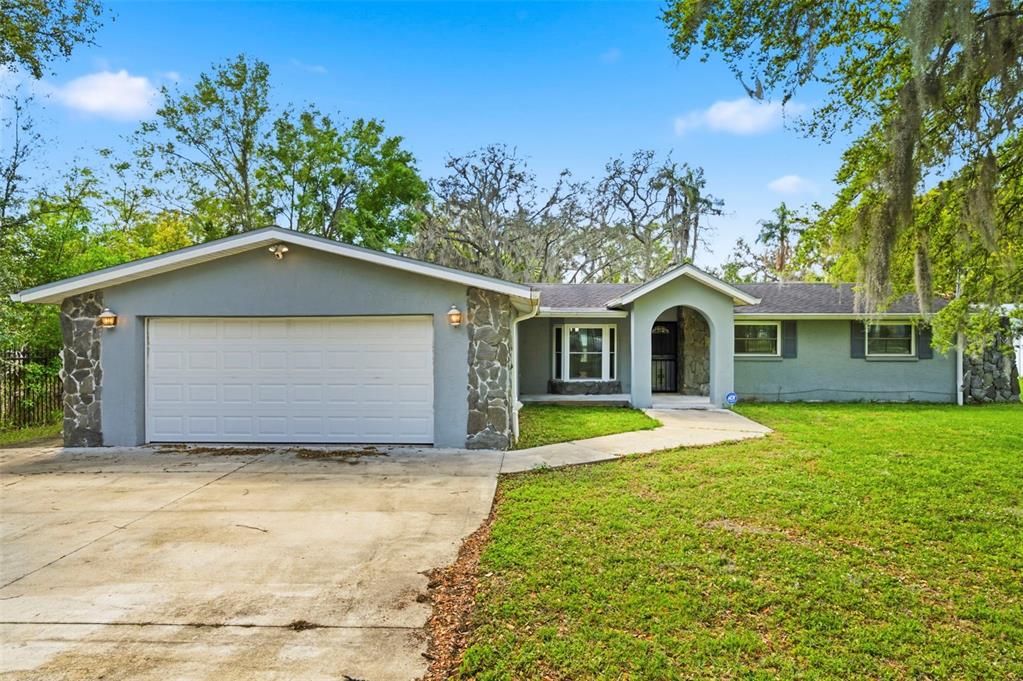 A single-story house with a gray exterior, stone accents, and an attached two-car garage — 212 W 131ST AVENUE, TAMPA, FL