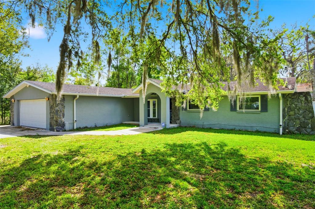 A single-story house with a gray stucco exterior, stone accents, and a two-car garage — 212 W 131ST AVENUE, TAMPA, FL