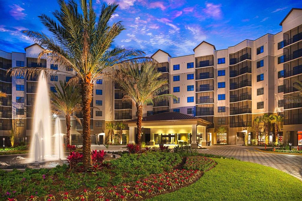 A multi-story apartment building exterior featuring a fountain, palm trees, and a covered entrance — 14501 GROVE RESORT AVENUE UNIT 1443, WINTER GARDEN, FL