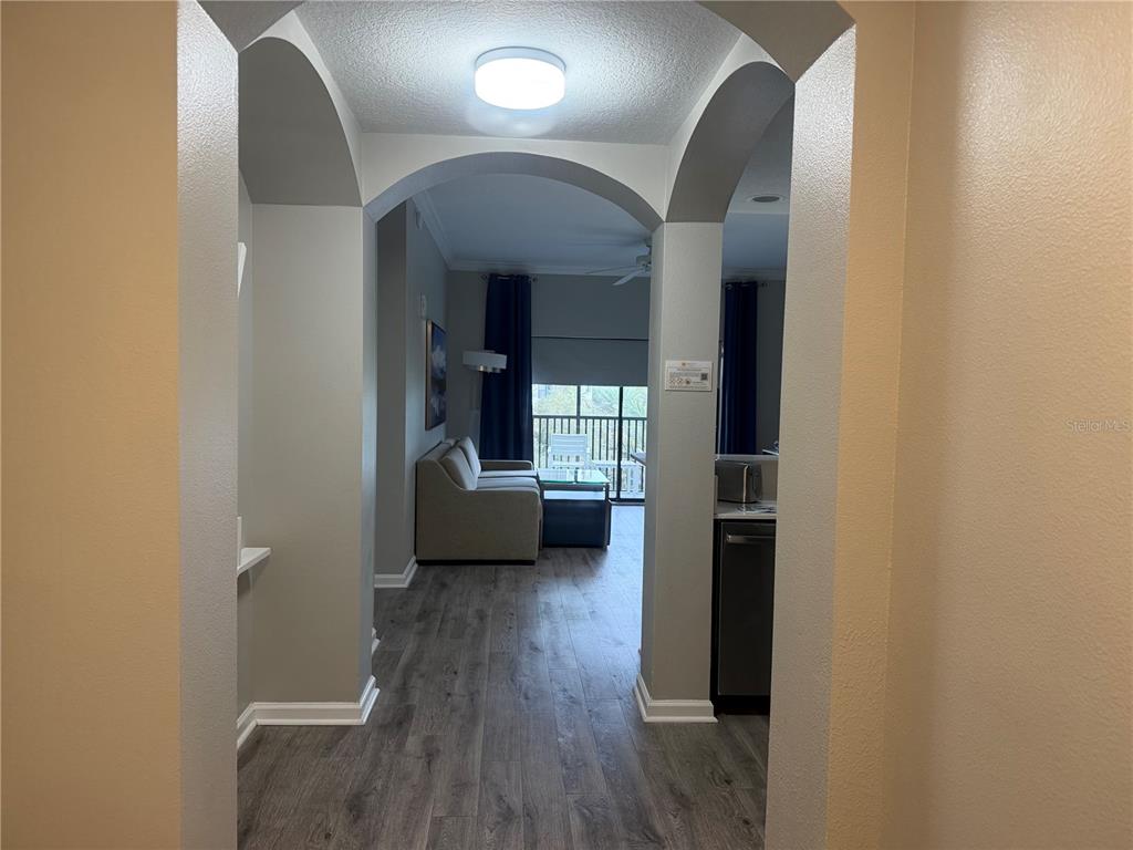 A view through an arched entryway into a living area with wood-look flooring and balcony — 14501 GROVE RESORT AVENUE UNIT 1443, WINTER GARDEN, FL
