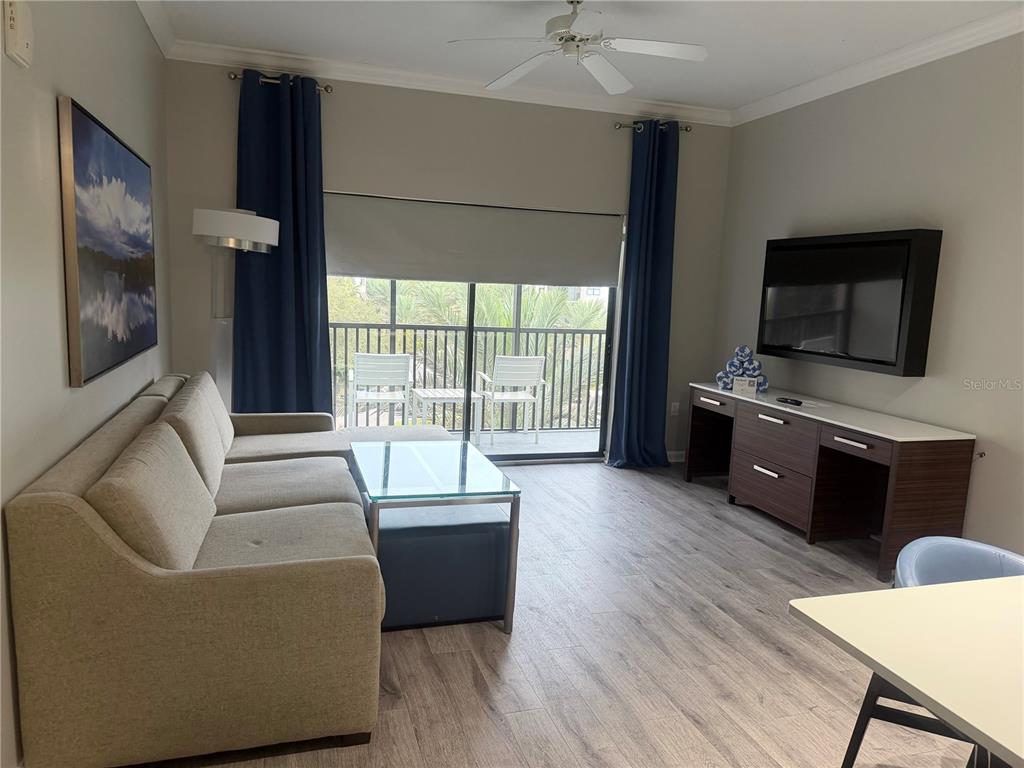 A living room features a beige sectional sofa, glass coffee table, media console, and balcony access — 14501 GROVE RESORT AVENUE UNIT 1443, WINTER GARDEN, FL