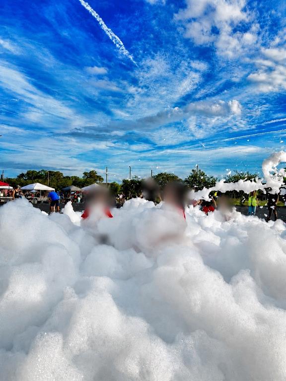 People play in a large pile of foam at an outdoor event under a blue sky — N/A N/A, OCALA, FL