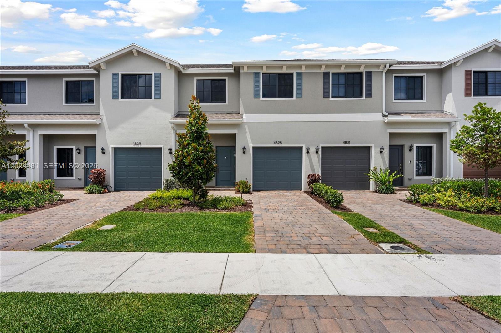 A row of three attached townhouses features gray stucco facades, dark garage doors, and brick driveways — 4825 Dillion St, Lake Worth FL 33463, LAKE WORTH, FL
