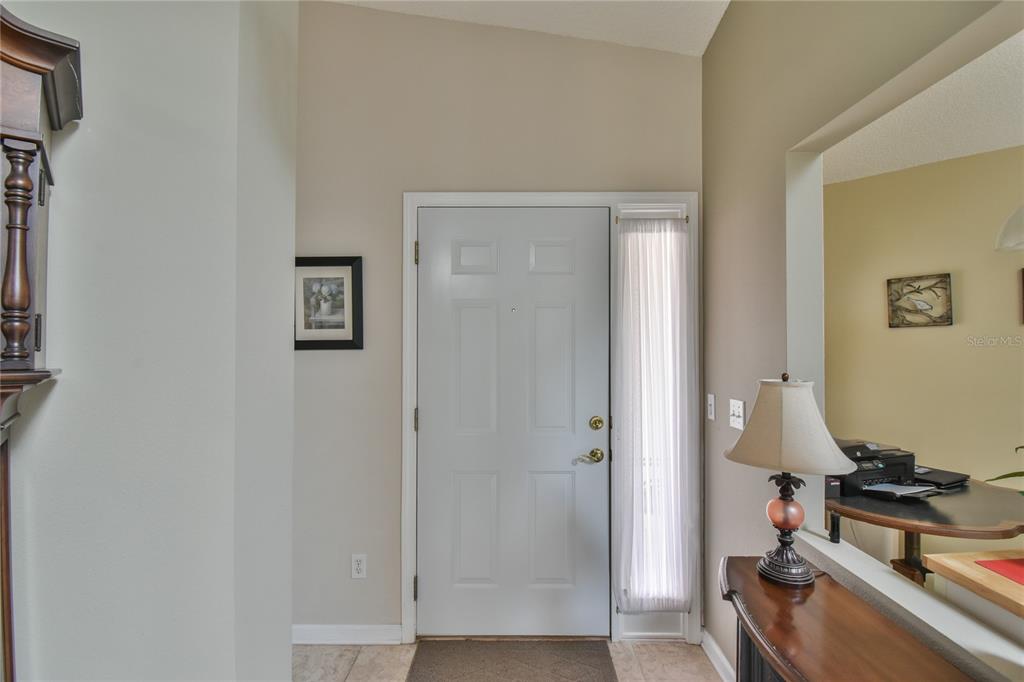 An entryway features a white front door with a sidelight, tile flooring, and a console table — 5247 NW 18TH STREET, OCALA, FL