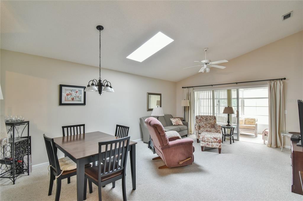 A dining area and living room with a vaulted ceiling, skylight, and sliding glass doors — 5247 NW 18TH STREET, OCALA, FL