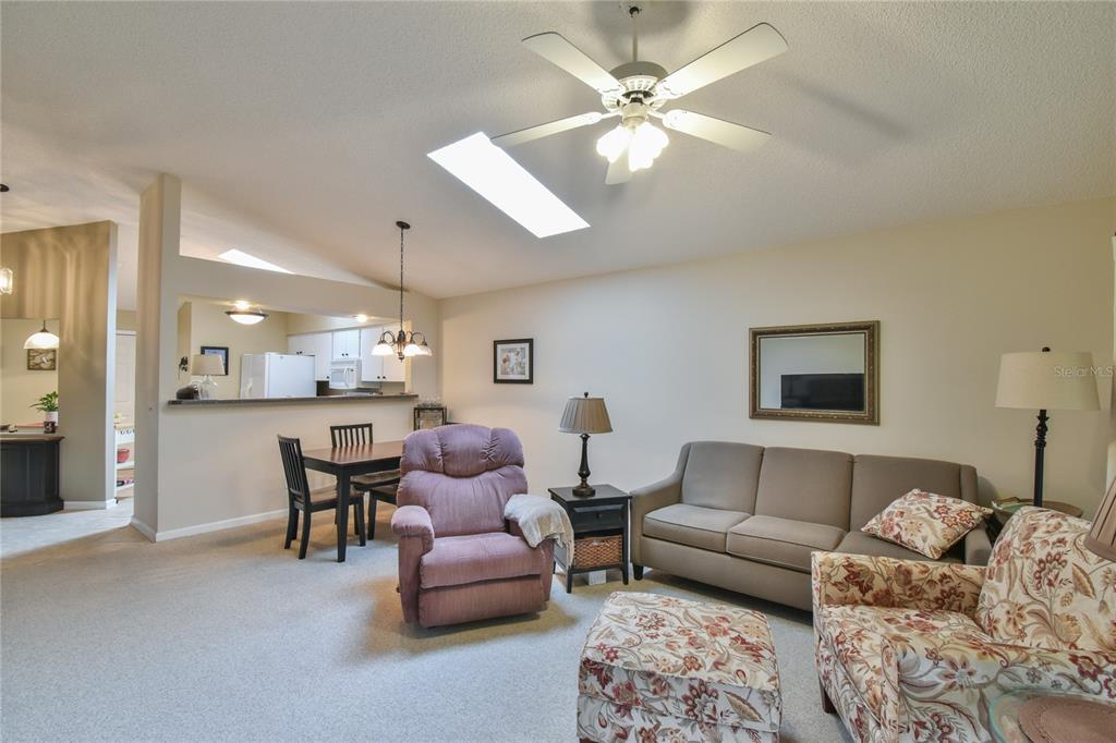 A living room with a beige sofa, floral armchair, recliner, and an open kitchen area — 5247 NW 18TH STREET, OCALA, FL