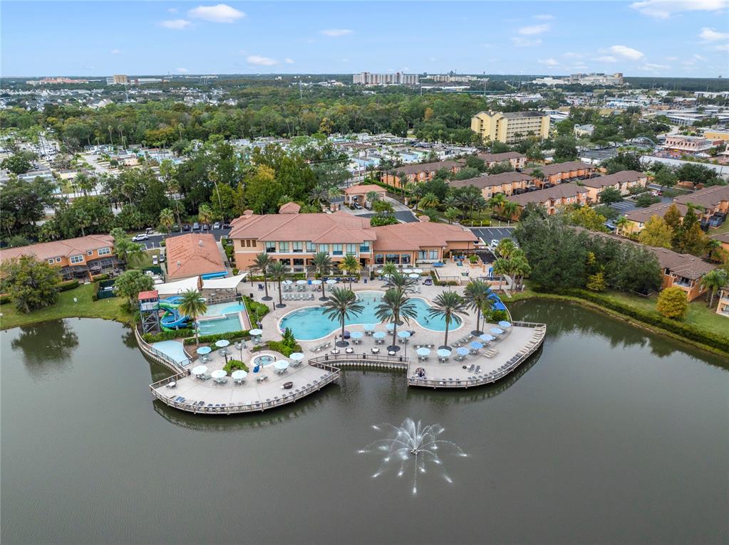 An aerial view of a resort-style swimming pool and clubhouse situated on a lake — 2754 CORVETTE LANE, KISSIMMEE, FL