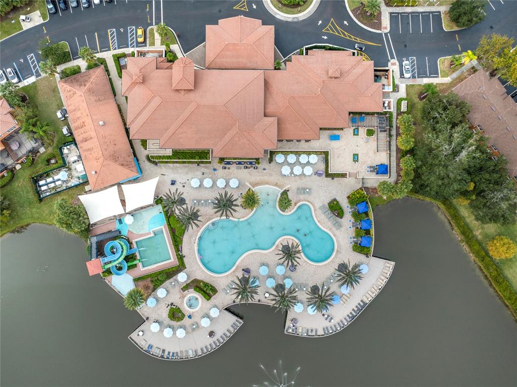 An aerial view shows a community clubhouse with a swimming pool, waterslide, and lakefront patio — 2754 CORVETTE LANE, KISSIMMEE, FL