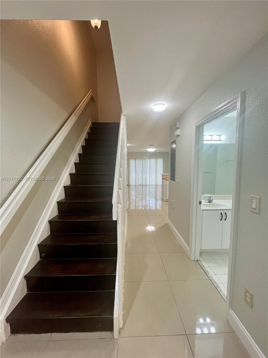 A staircase with dark wood treads leads upward next to a hallway and bathroom — 3028 SW 129th Ter # 120, Miramar FL 33027, MIRAMAR, FL