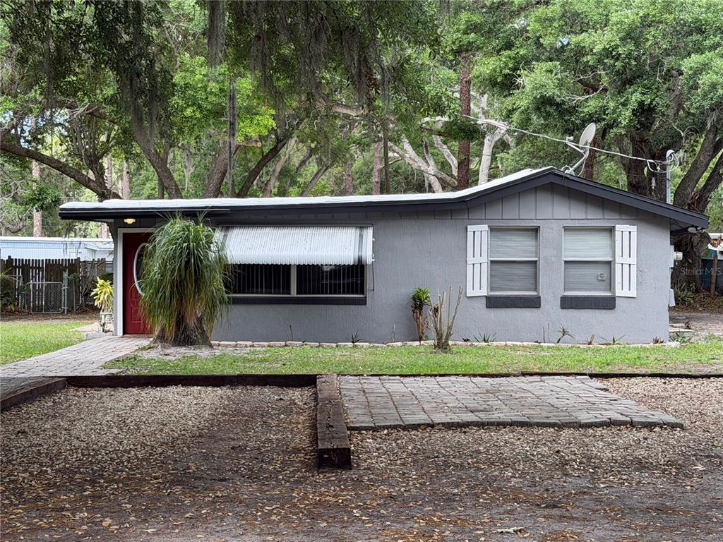 A single-story gray house with a red front door and a gravel driveway — 1257 LYNCHBURG ROAD, LAKE ALFRED, FL