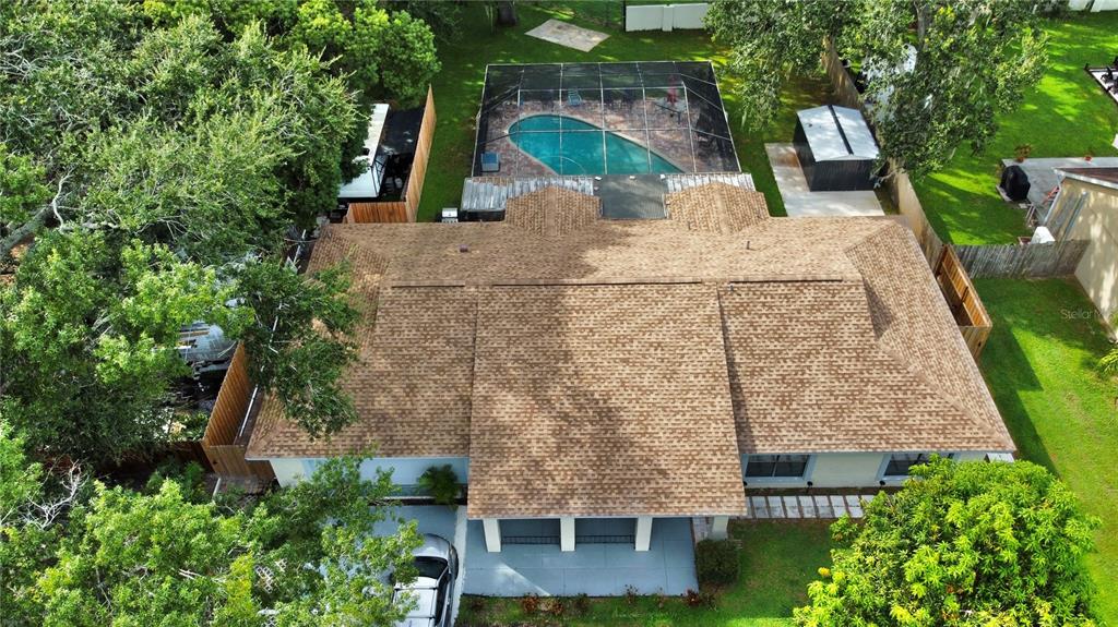 An aerial view shows a house with a shingled roof, a screened-in pool, and trees — 14216 BRIARTHORN DRIVE, TAMPA, FL
