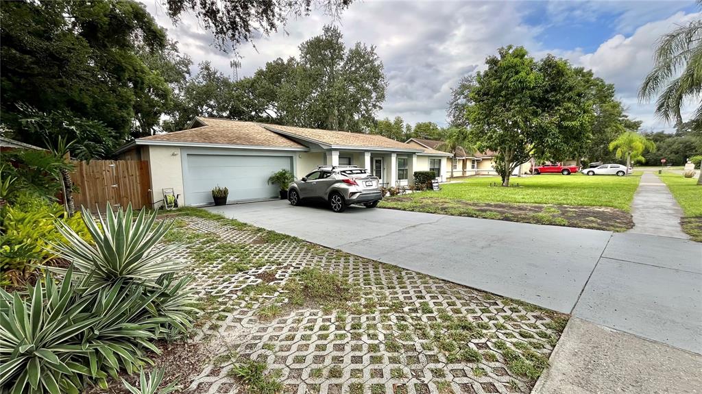 A single-story house with a light-colored exterior, a garage, and a concrete driveway — 14216 BRIARTHORN DRIVE, TAMPA, FL