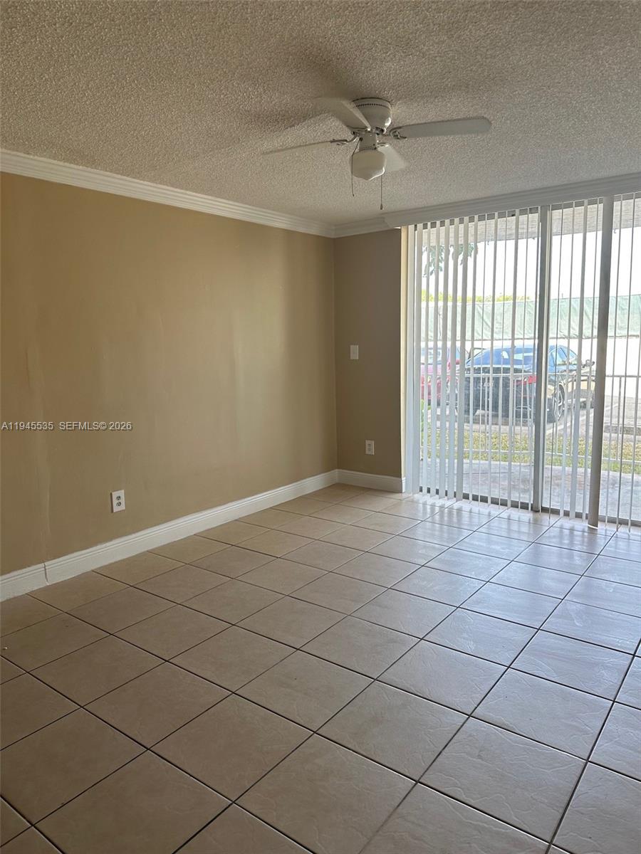 An empty room features beige walls, light-colored floor tiles, a ceiling fan, and sliding doors — 488 NW 165th St Rd # 115, Miami FL 33169, MIAMI, FL