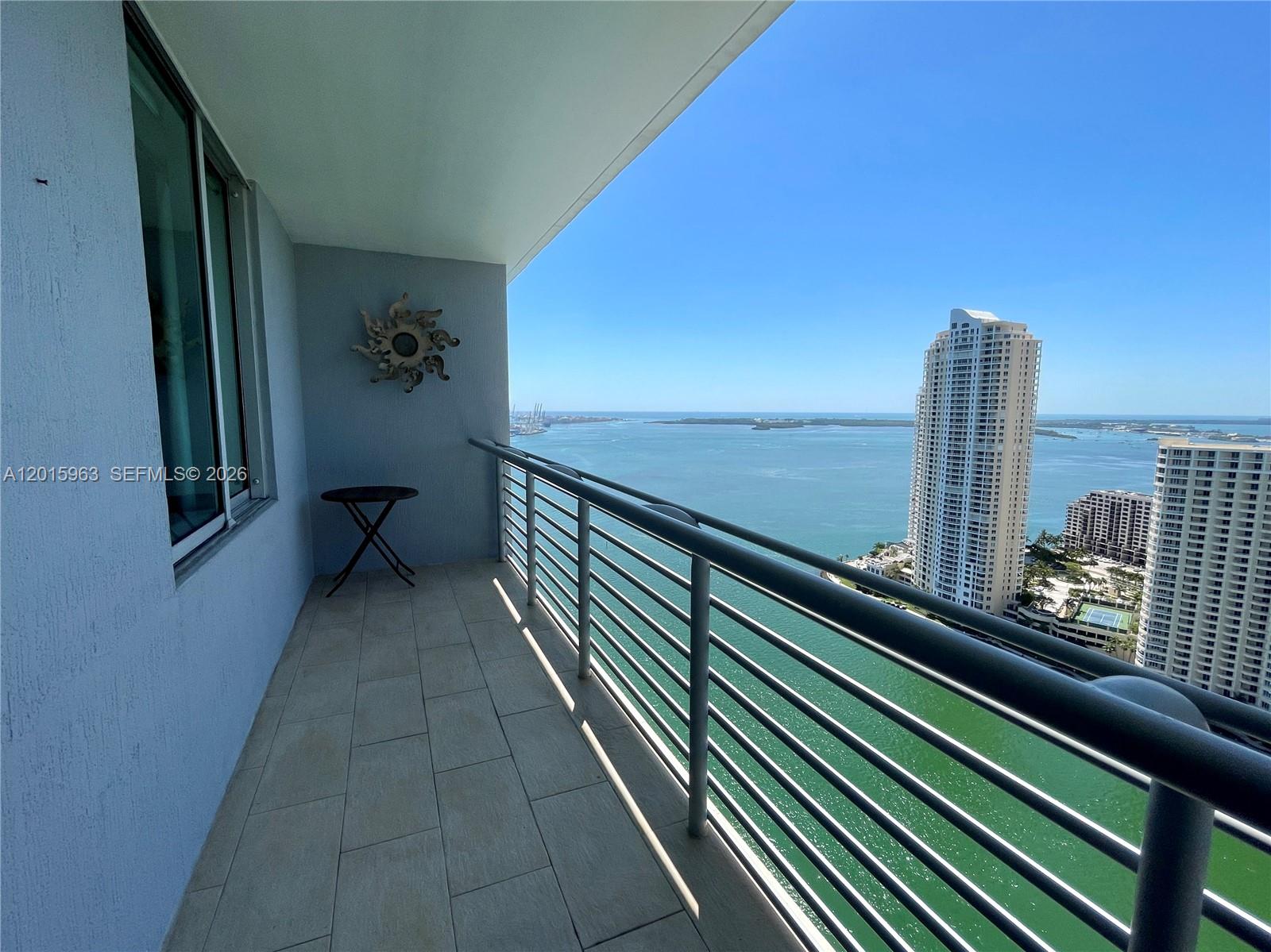 A balcony with tile flooring and a metal railing overlooks a bay and city skyline — 335 S Biscayne Blvd # 3603, Miami FL 33131, MIAMI, FL
