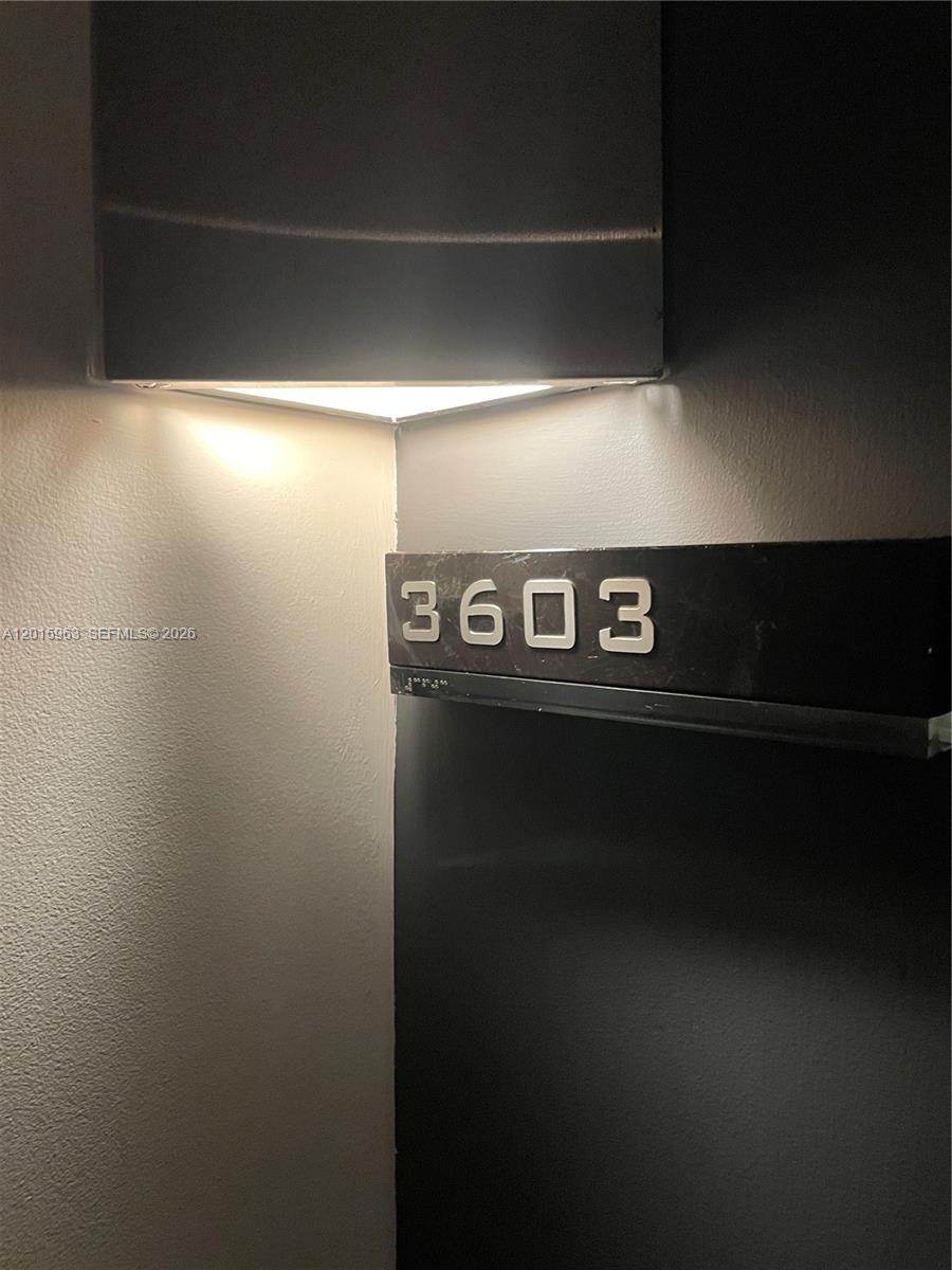 A wall-mounted light fixture illuminates a dark sign displaying the number 3603 — 335 S Biscayne Blvd # 3603, Miami FL 33131, MIAMI, FL