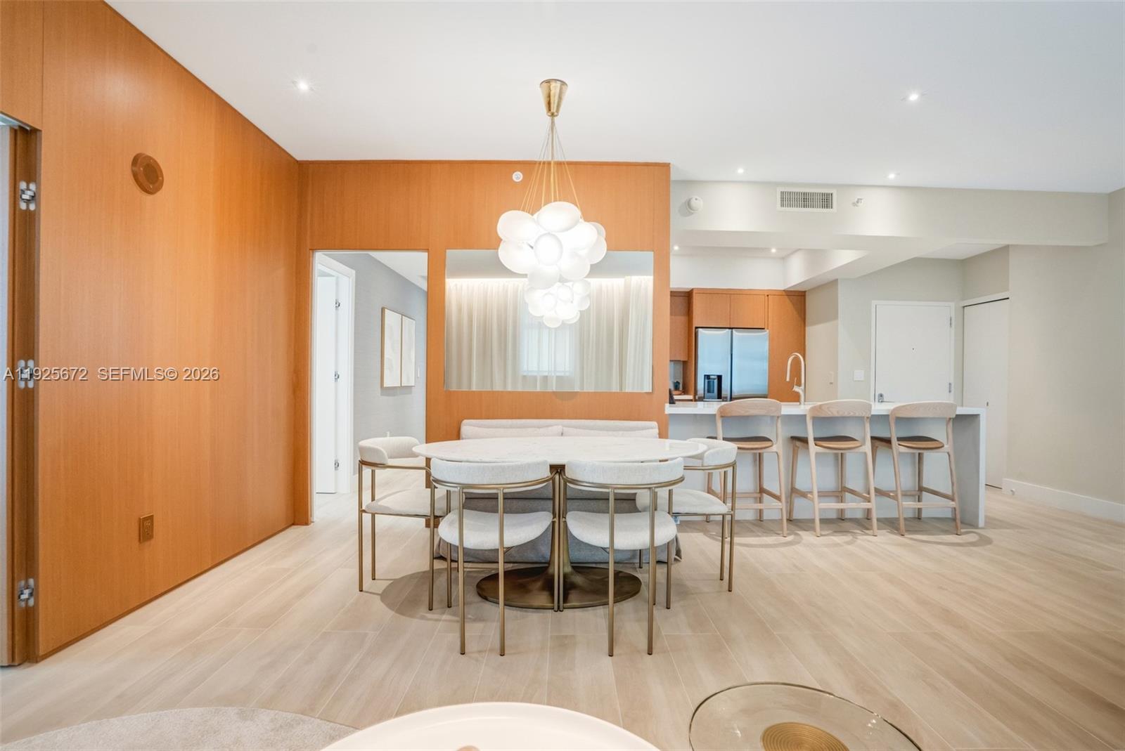A modern open-plan living and dining area features neutral tones, curved furniture, and gold accents — 31 SE 5th St # 3921, Miami FL 33131, MIAMI, FL