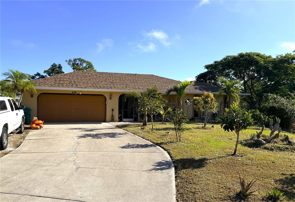 A single-story house with a brown garage door and a concrete driveway under blue skies — 4114 COLLINGSWOOD BOULEVARD, PORT CHARLOTTE, FL
