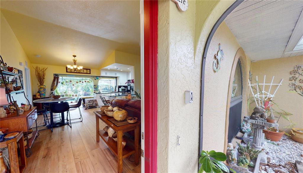 A view from a covered porch looking into a living room with wood-look flooring — 4114 COLLINGSWOOD BOULEVARD, PORT CHARLOTTE, FL