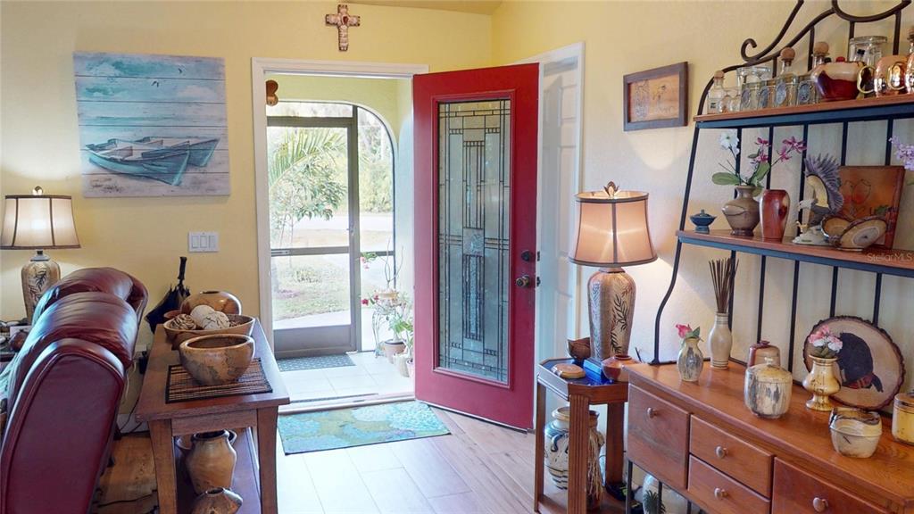 An entryway features a red front door, wood flooring, and a decorative metal shelving unit — 4114 COLLINGSWOOD BOULEVARD, PORT CHARLOTTE, FL