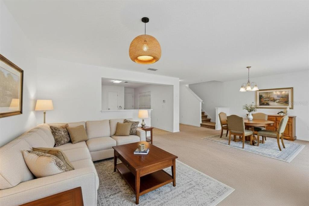 A living and dining room with beige carpet, neutral furniture, and a woven pendant light — 13759 GOLDEN RUSSET DRIVE, WINTER GARDEN, FL