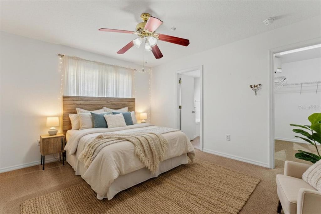 A bedroom features a bed with a wood headboard, a ceiling fan, and carpeted flooring — 13759 GOLDEN RUSSET DRIVE, WINTER GARDEN, FL