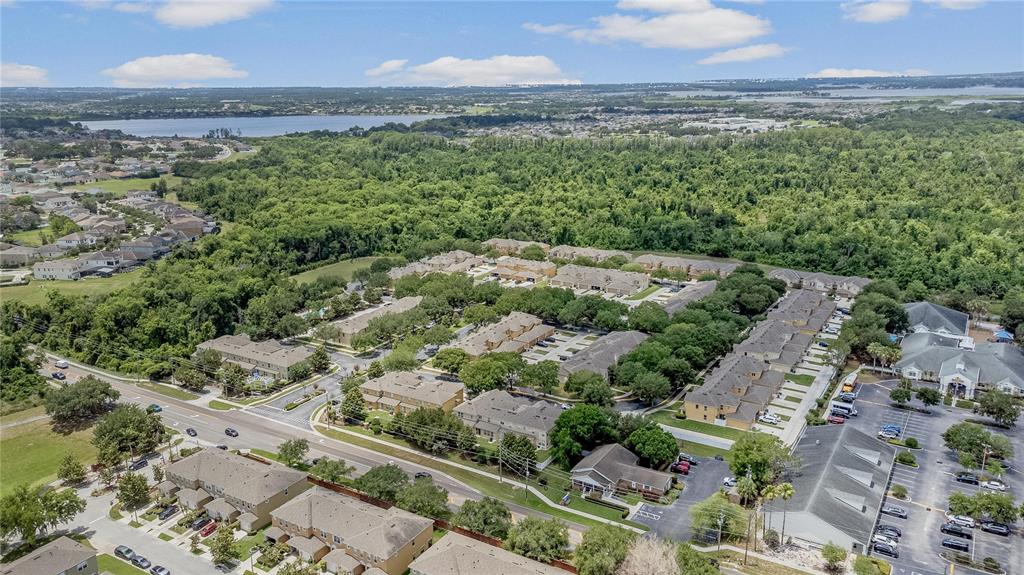 An aerial view shows a residential complex with multi-story buildings, parking lots, and surrounding trees — 13759 GOLDEN RUSSET DRIVE, WINTER GARDEN, FL