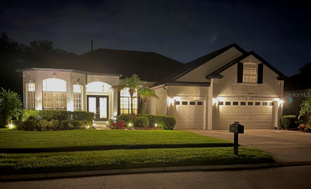 A single-story house with a multi-car garage and illuminated landscaping at night — 2848 ALOMA LAKE RUN, OVIEDO, FL