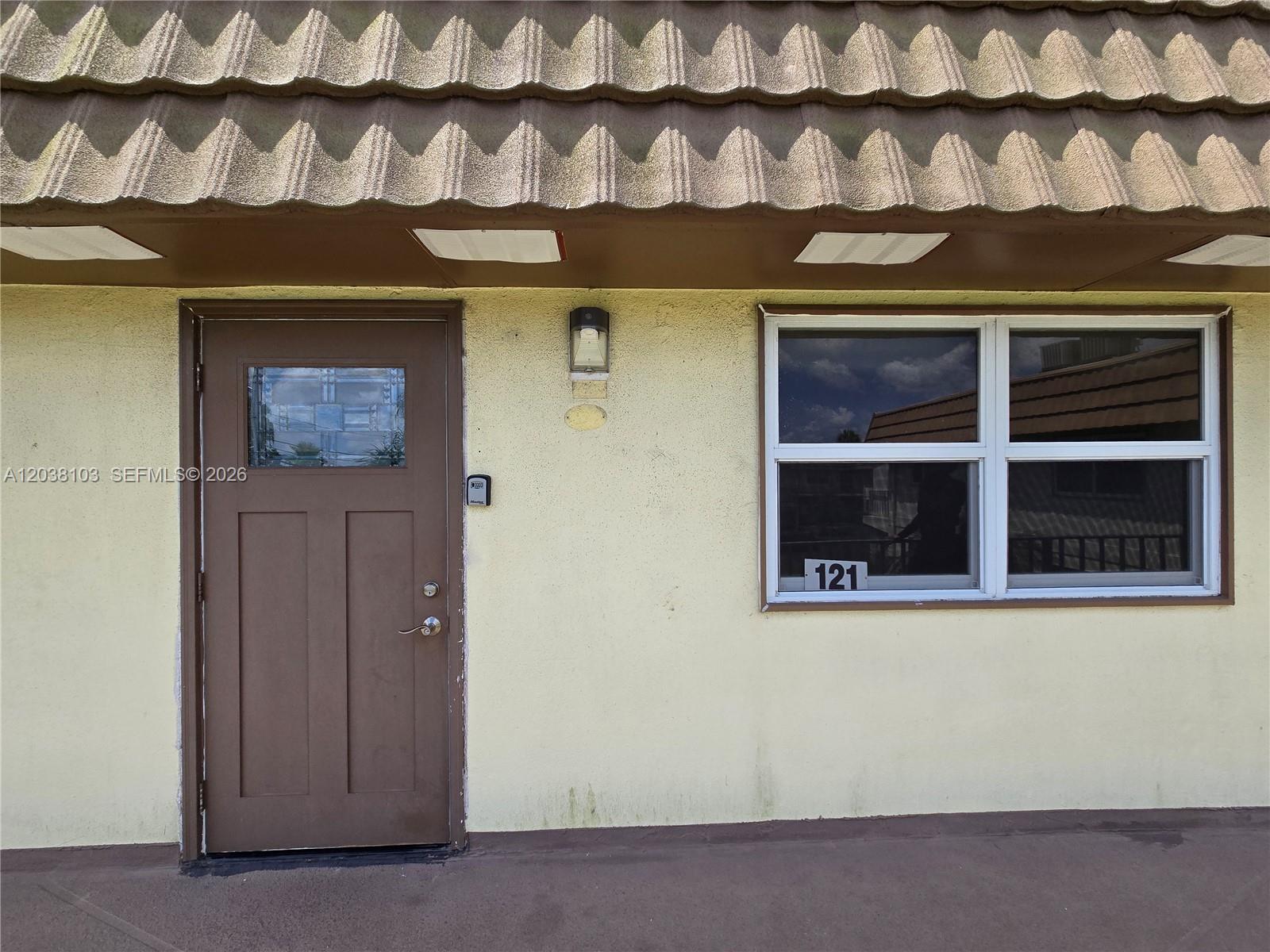 A brown door and a window labeled 121 are on the exterior of a building — 121 Saxony C # 121, Delray Beach FL 33446, DELRAY BEACH, FL