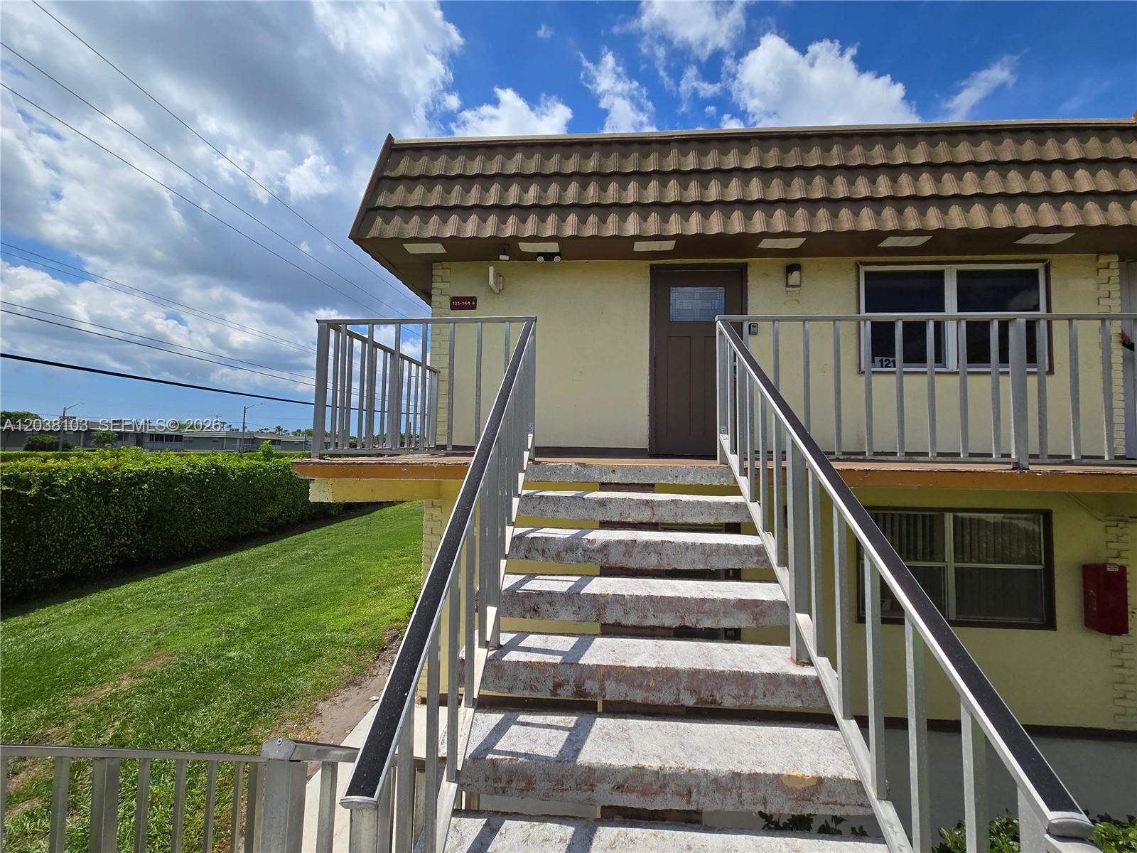 An exterior view shows a concrete staircase leading to an elevated walkway and apartment entrance — 121 Saxony C # 121, Delray Beach FL 33446, DELRAY BEACH, FL