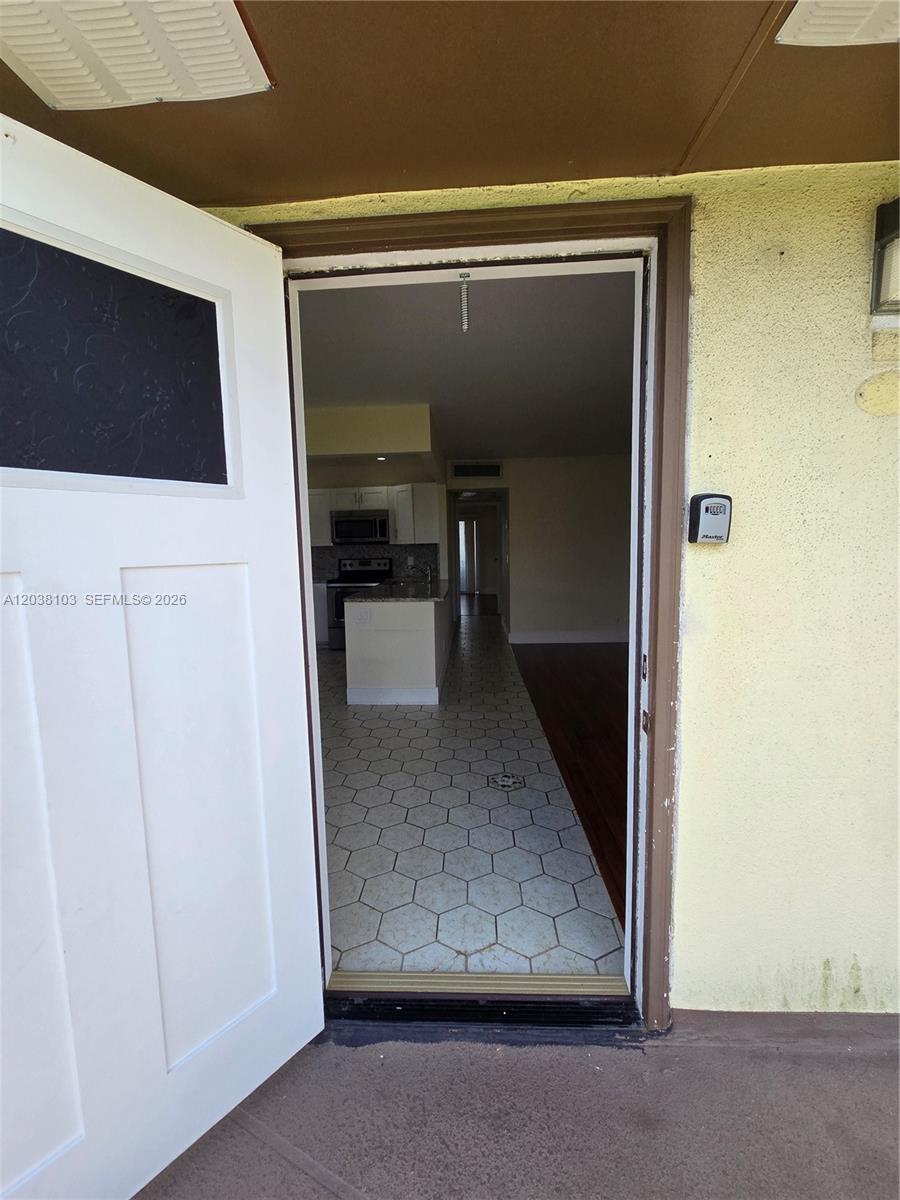 A view through an open door shows a kitchen with white cabinets and hexagonal flooring — 121 Saxony C # 121, Delray Beach FL 33446, DELRAY BEACH, FL