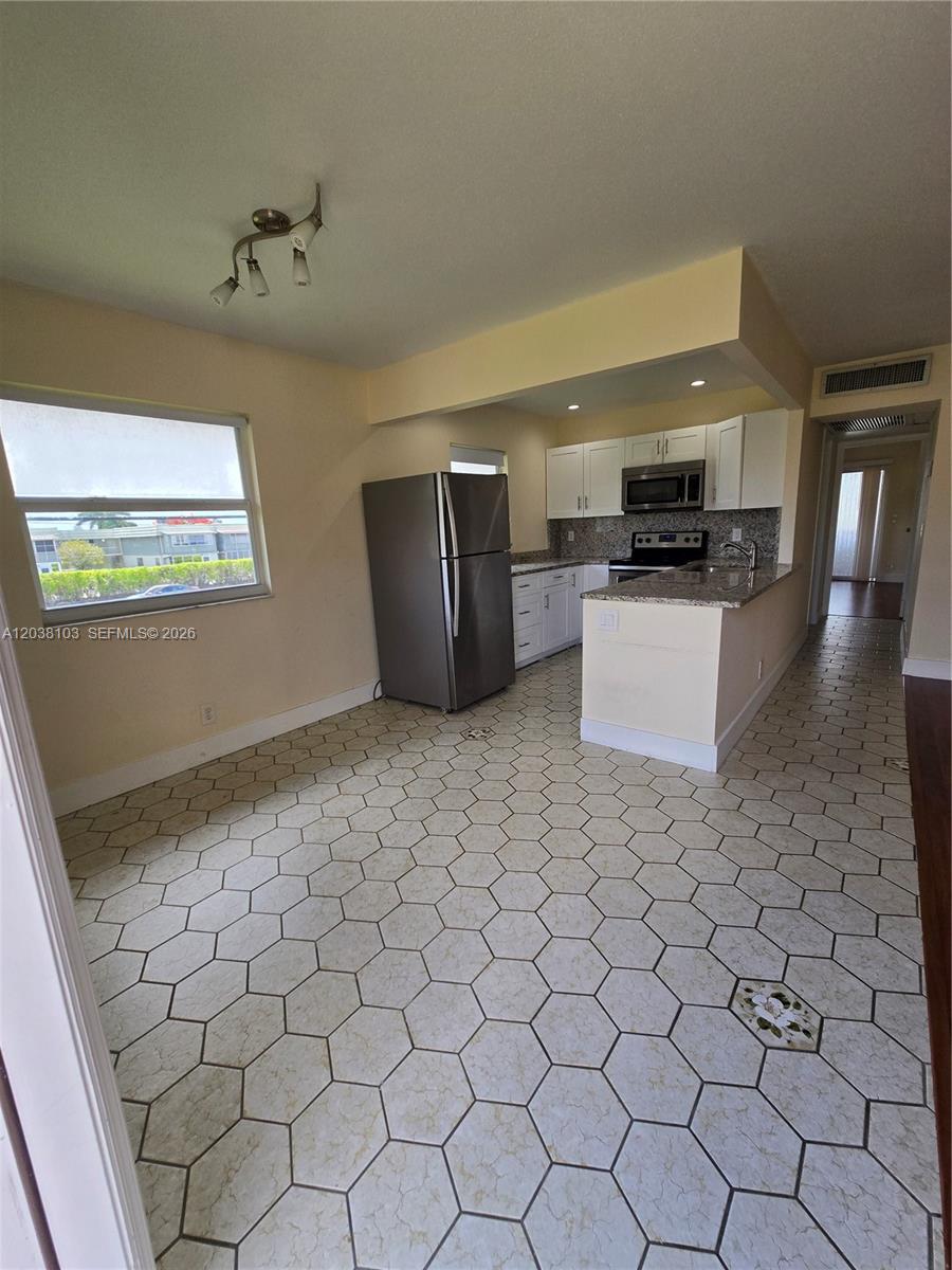 A kitchen with white cabinets, granite countertops, and hexagonal tile flooring — 121 Saxony C # 121, Delray Beach FL 33446, DELRAY BEACH, FL