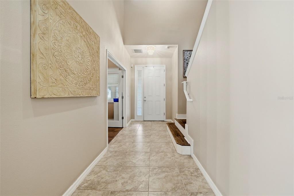 A tiled entryway features a high ceiling, a staircase, and a doorway leading to another room — 24115 SAN GIOVANNI DRIVE, LAND O LAKES, FL