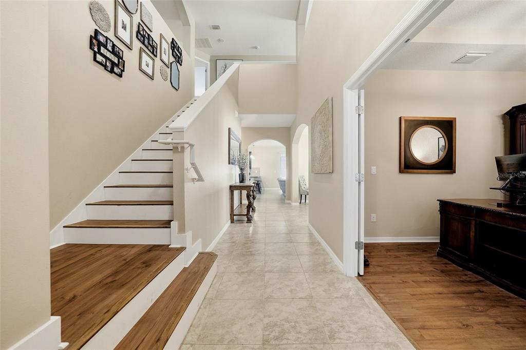 A foyer with a staircase, tile flooring, and an adjacent room with wood flooring — 24115 SAN GIOVANNI DRIVE, LAND O LAKES, FL