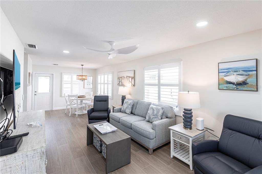 A living room with a grey sofa, two dark recliners, and a dining area — 6020 MIDNIGHT PASS ROAD UNIT 29, SARASOTA, FL