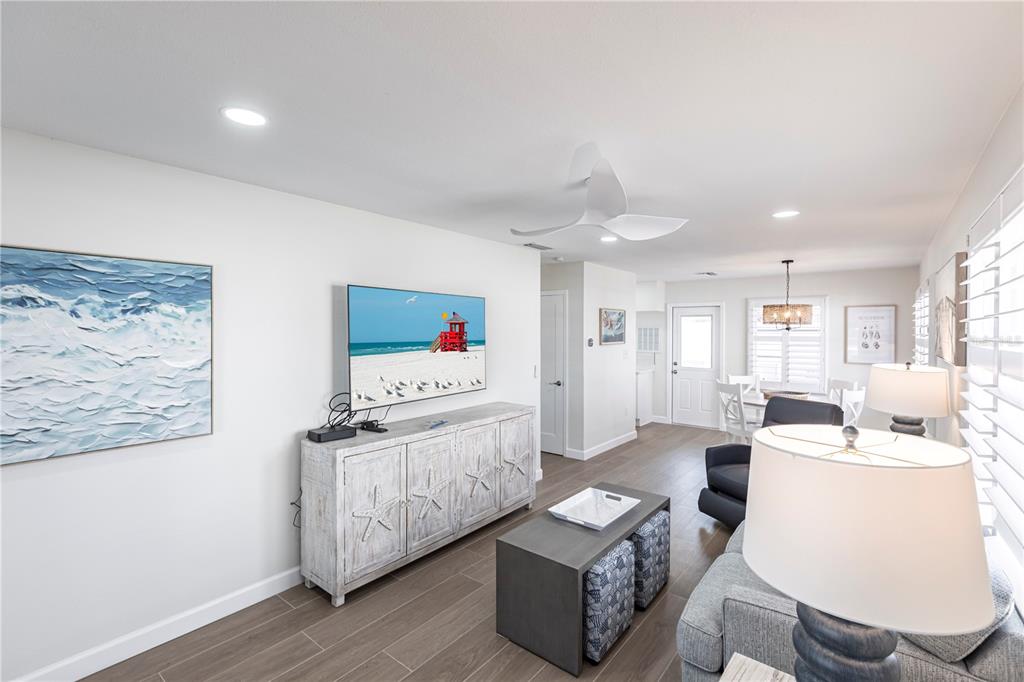 A living room features a television, a white sideboard, a coffee table, and wood-look flooring — 6020 MIDNIGHT PASS ROAD UNIT 29, SARASOTA, FL
