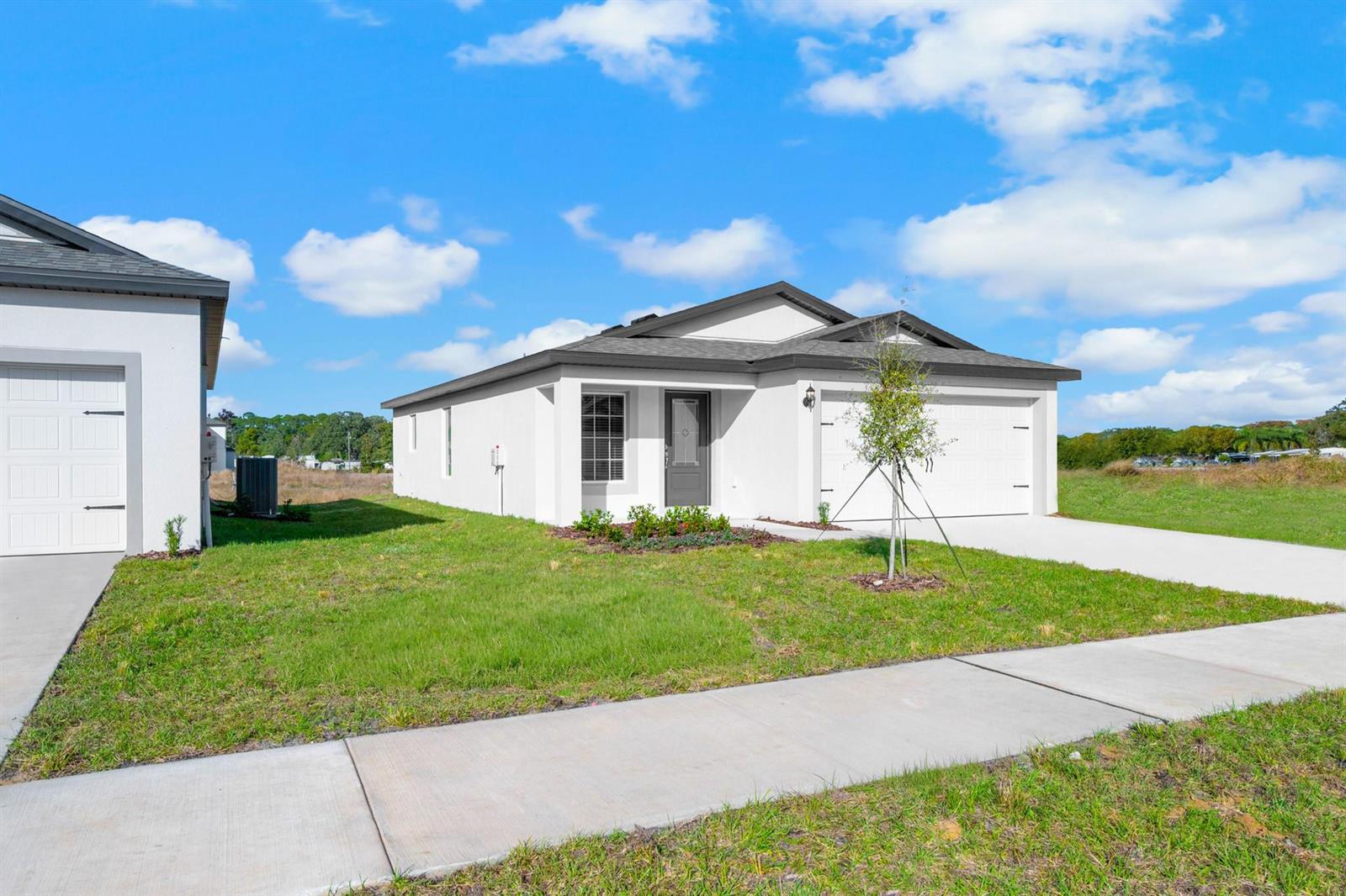 A white single-story house with a two-car garage sits on a grassy lot — 8436 100th Court, Vero Beach FL 32967, VERO BEACH, FL