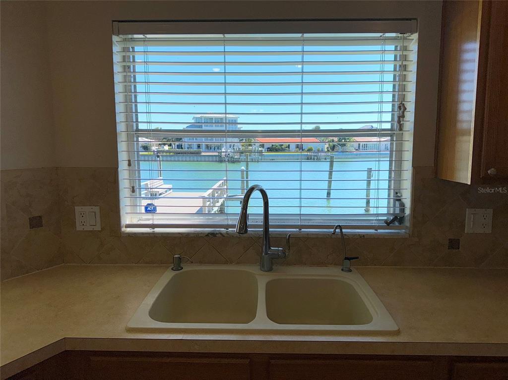A kitchen sink with a faucet sits in front of a window overlooking a canal — 228 HOWARD DRIVE, BELLEAIR BEACH, FL