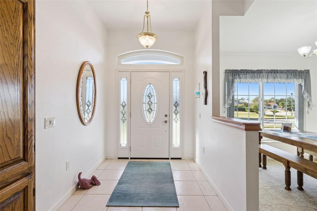 A tiled entryway features a white front door with sidelights, a pendant light, and mirror — 217 KENT COURT, HAINES CITY, FL