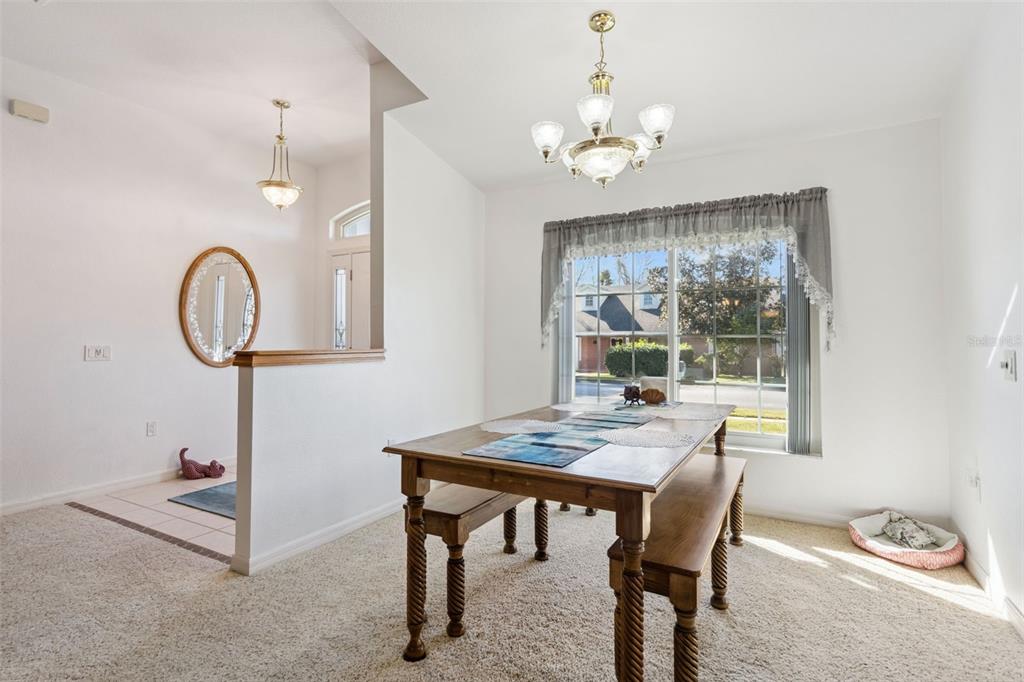 A dining area features a wooden table with benches, a chandelier, and a large window — 217 KENT COURT, HAINES CITY, FL
