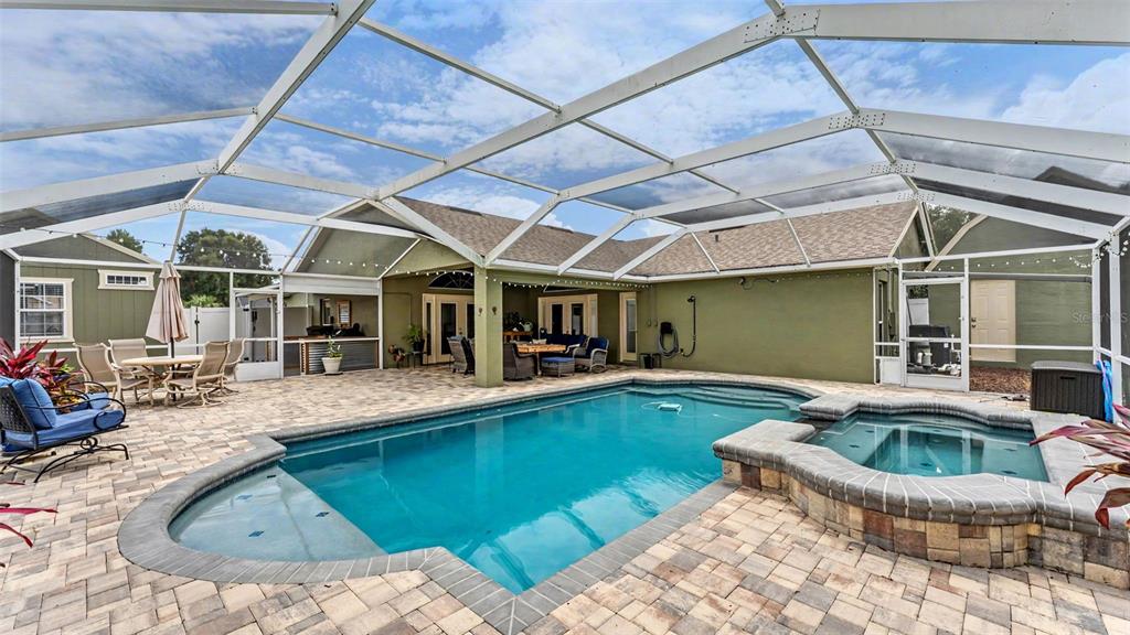 A screened-in patio features a swimming pool, a raised spa, and paved decking — 36225 OAK KNOLL LOOP, DADE CITY, FL