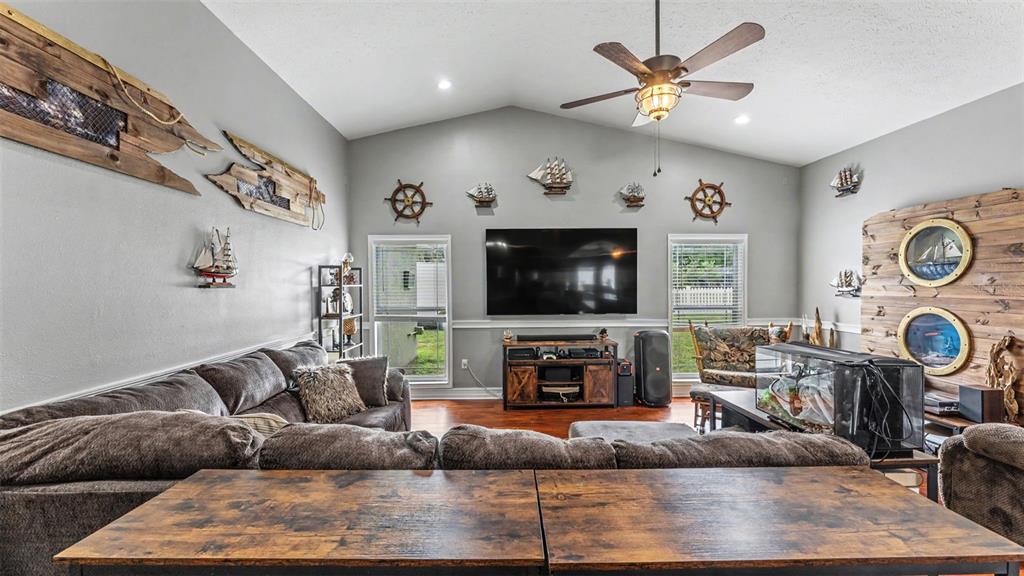 A living room features nautical decor, a large television, and a sectional sofa — 36225 OAK KNOLL LOOP, DADE CITY, FL