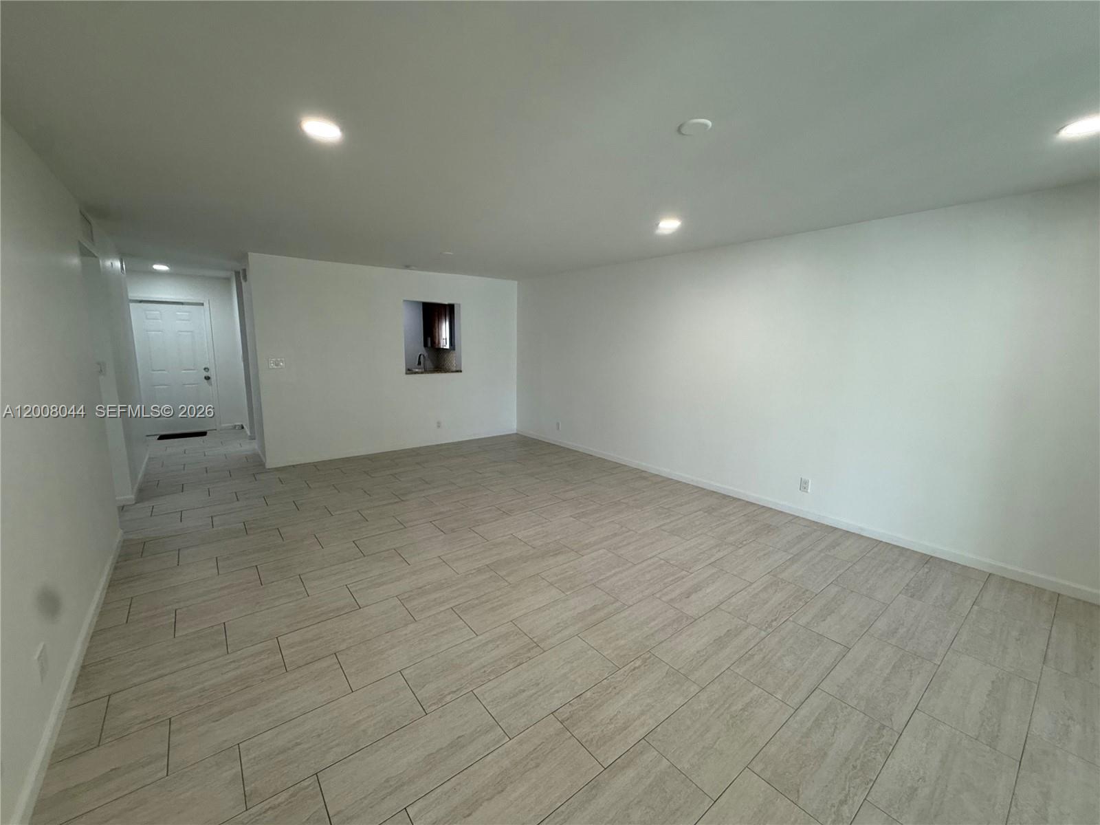 A spacious, empty room features white walls, recessed lighting, and light-colored wood-look tile flooring — 609 NE 14th Ave # 108, Hallandale Beach FL 33009, HALLANDALE BEACH, FL