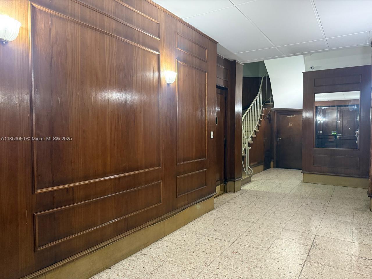 A hallway features wood-paneled walls, a tiled floor, a staircase, and a mirror — 128 Bernardo de Irigoyen Montserrat # 7, FL 128, FL