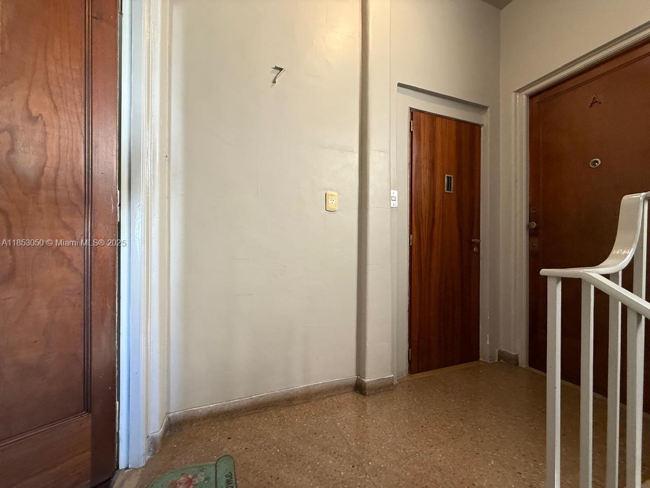 A hallway features beige tile flooring, light-colored walls, and two wooden doors — 128 Bernardo de Irigoyen Montserrat # 7, FL 128, FL