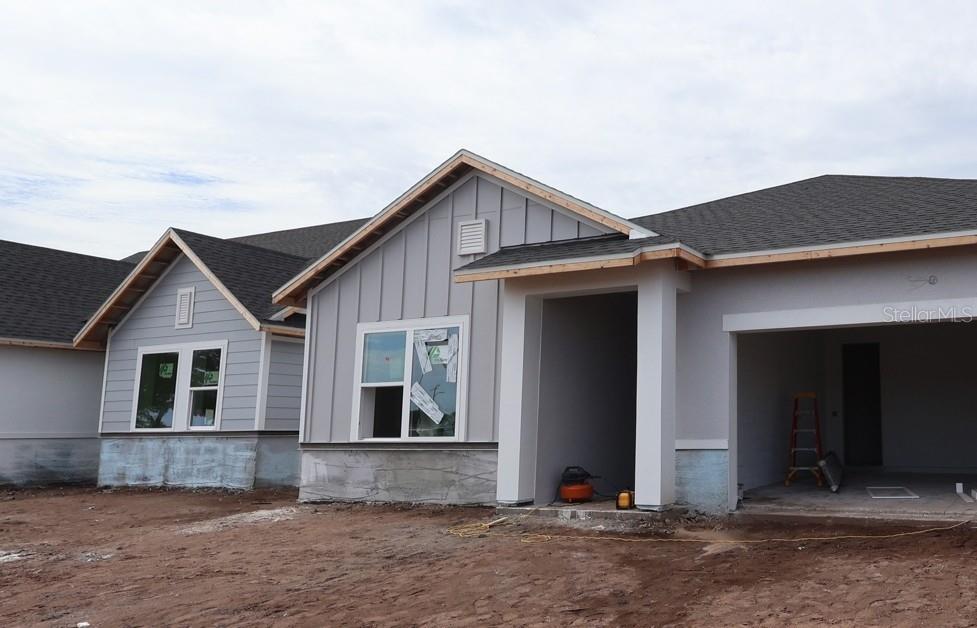 The exterior of a new construction house features gray board-and-batten siding and a covered entryway — 5027 ORINOCO LANE, ST CLOUD, FL