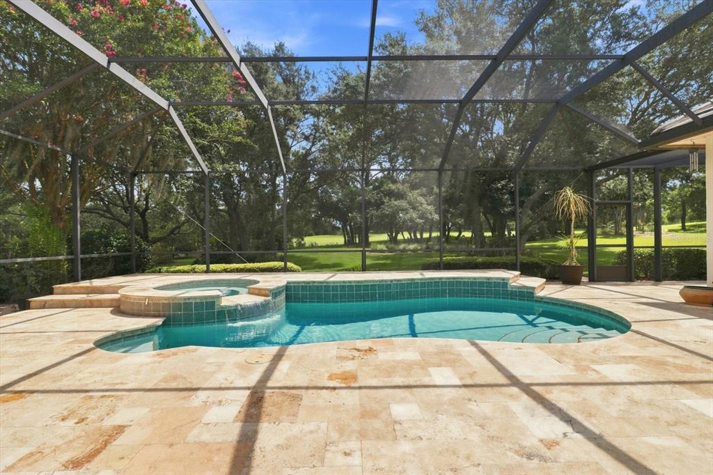 A screened-in pool and spa area with stone decking overlooking a grassy backyard — 3405 N SPYGLASS VILLAGE PATH, LECANTO, FL