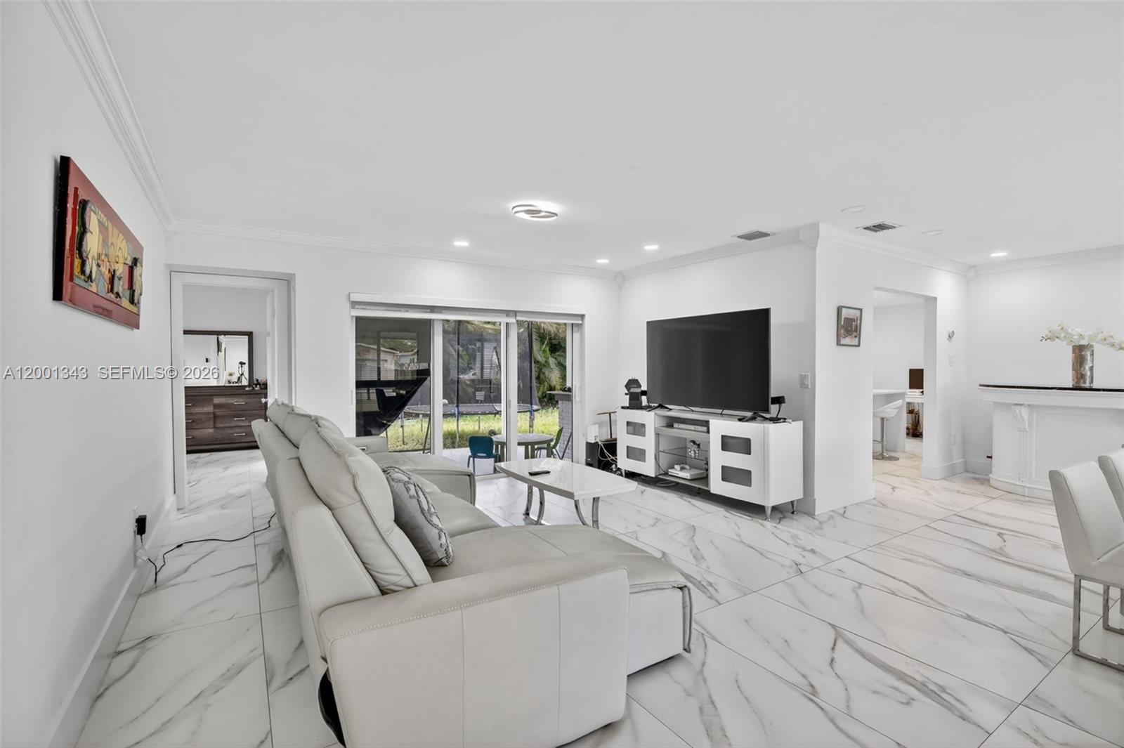 A living room features white marble-look tile floors, a white sectional sofa, and sliding doors — 9280 SW 55th Ct, Cooper City FL 33328, COOPER CITY, FL