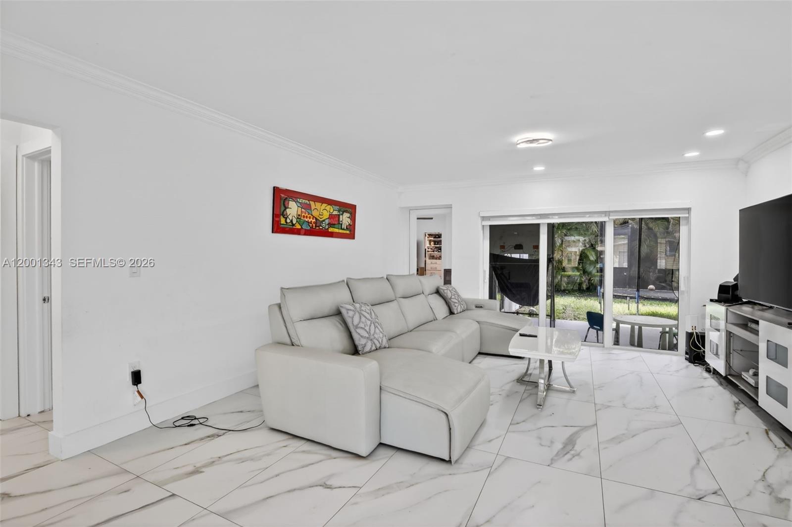 A living room features a light gray sectional sofa, white marble-look tile floors, and sliding doors — 9280 SW 55th Ct, Cooper City FL 33328, COOPER CITY, FL