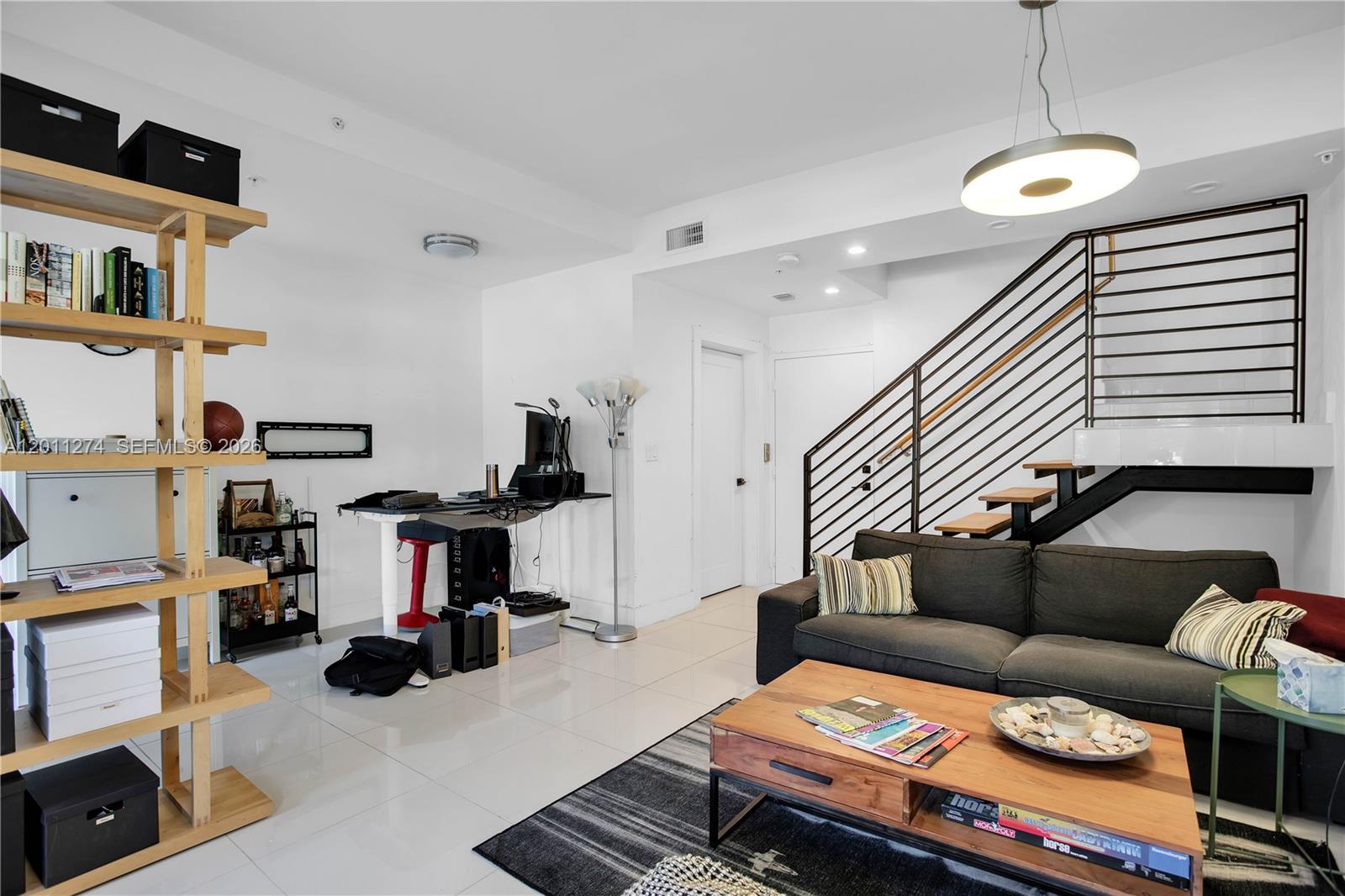 A living room features a dark sofa, a wooden coffee table, and a staircase — 87 N Shore Dr, Miami Beach FL 33141, MIAMI BEACH, FL